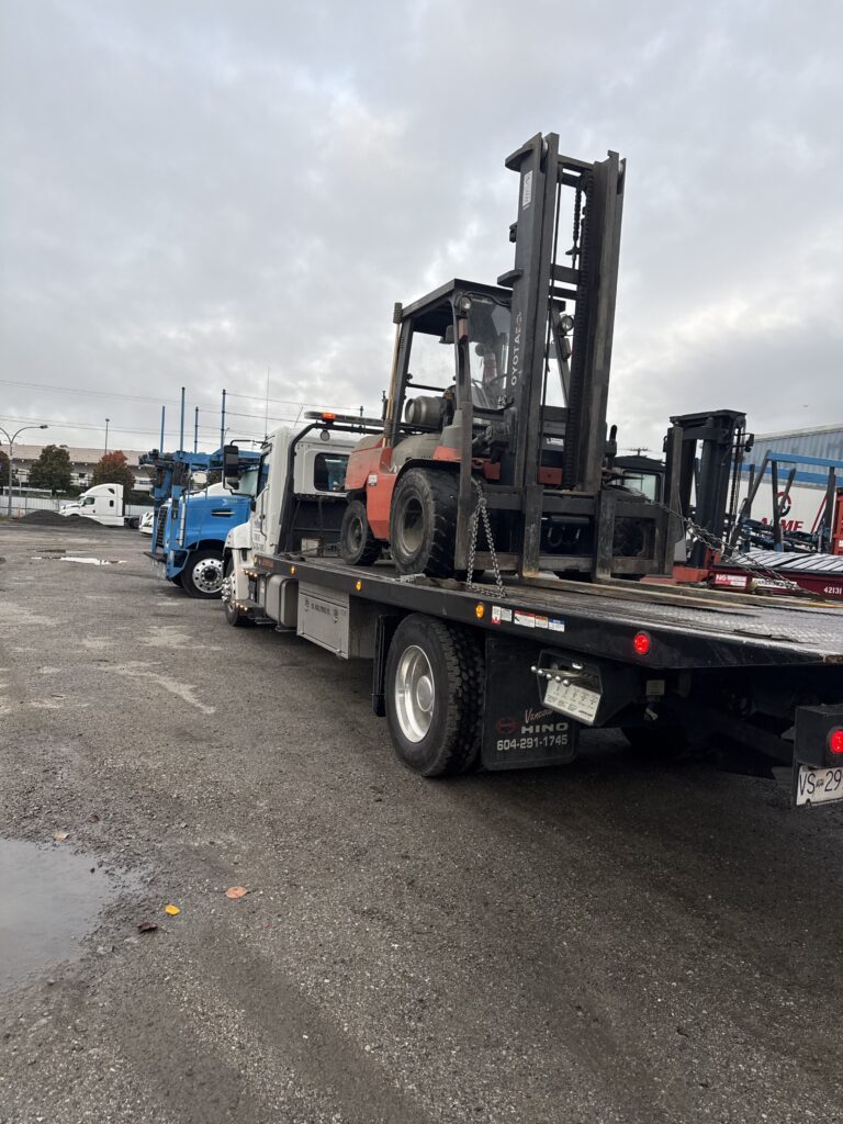 Heavy equipment removal near me in action as a Toyota forklift is loaded onto our tow truck