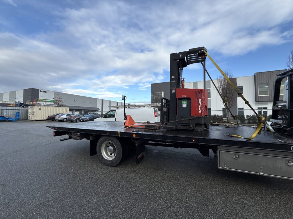 Old machinery pickup service loading an electric reach truck forklift onto our flatbed in Burnaby